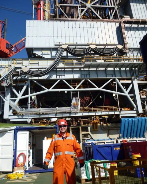 Paul L. Angus in orange coveralls and a hard hat on the Montara wellhead platform.