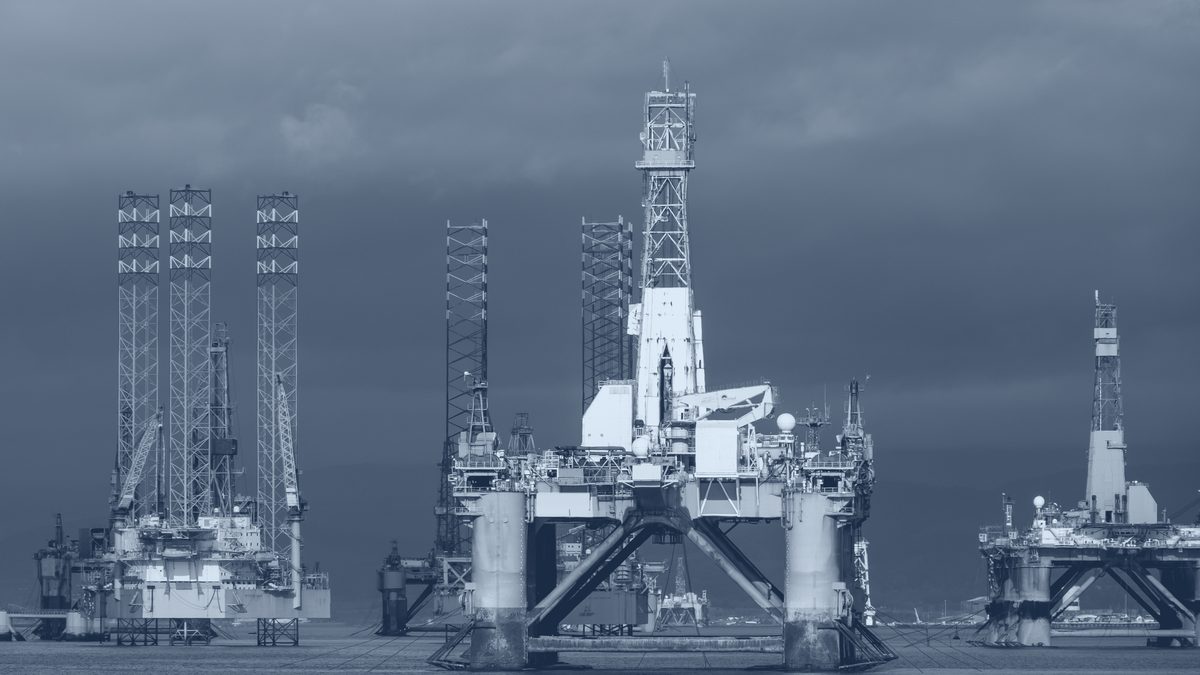 Drilling rigs at anchor under a storm sky.
