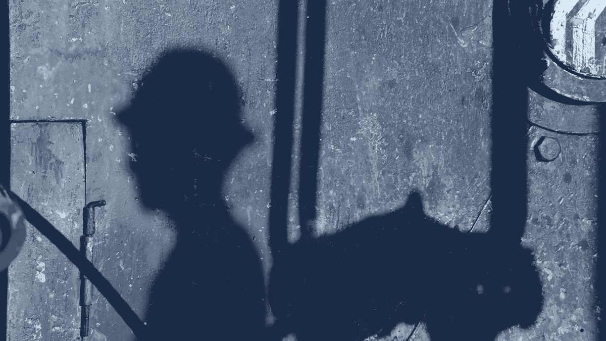 Shadow of an oil worker on the steel structure of a rig.